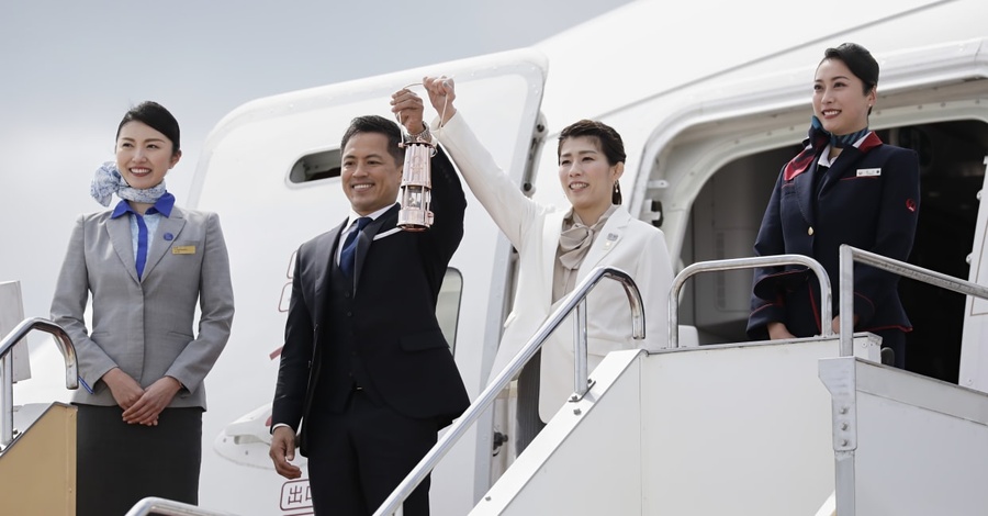 Japanese athletes Tadahiro Nomura and Saori Yoshida hold the Olympic Torch Relay Lantern aloft. © Tokyo 2020/Uta Mukuo