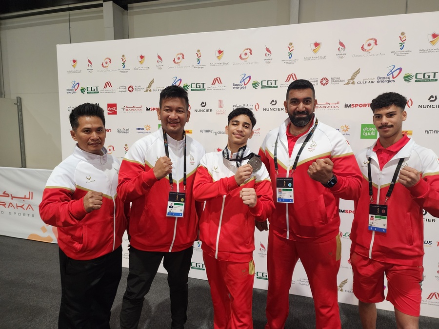 Bahrain's Abdulla Qassim (centre) shows off his silver medal in Pencak SIlat with two Indonesian coaches on his right © OCA