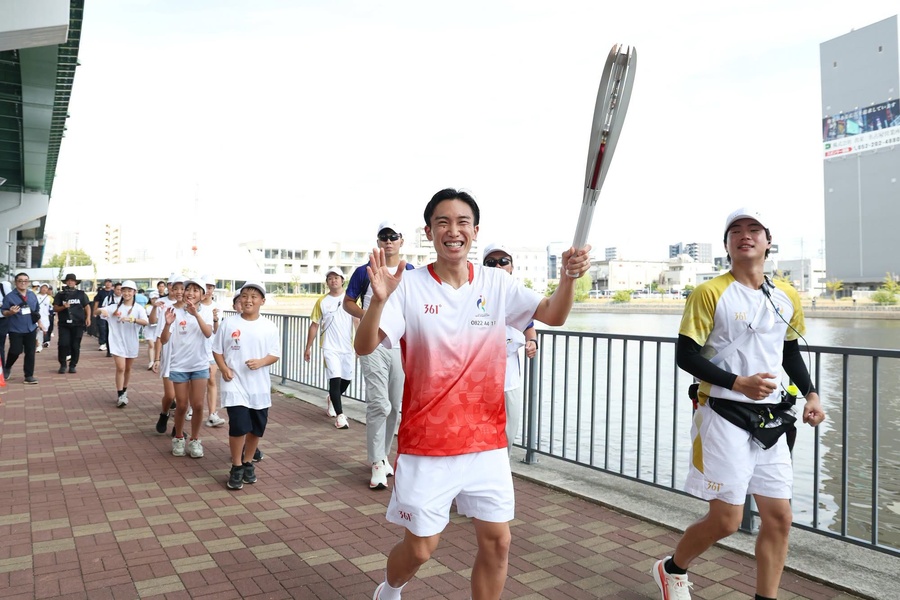 The torch relay is well underway through all 40 municipalities of Aichi Prefecture. Here, badminton star Kento Momota carries the torch. (Photo: AINAGOC)