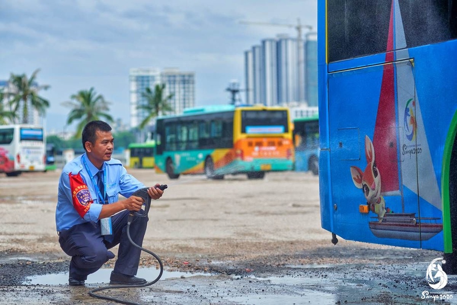 Zhou Xianli cleaning the Asian Beach Games-themed bus. © Feng Shuo