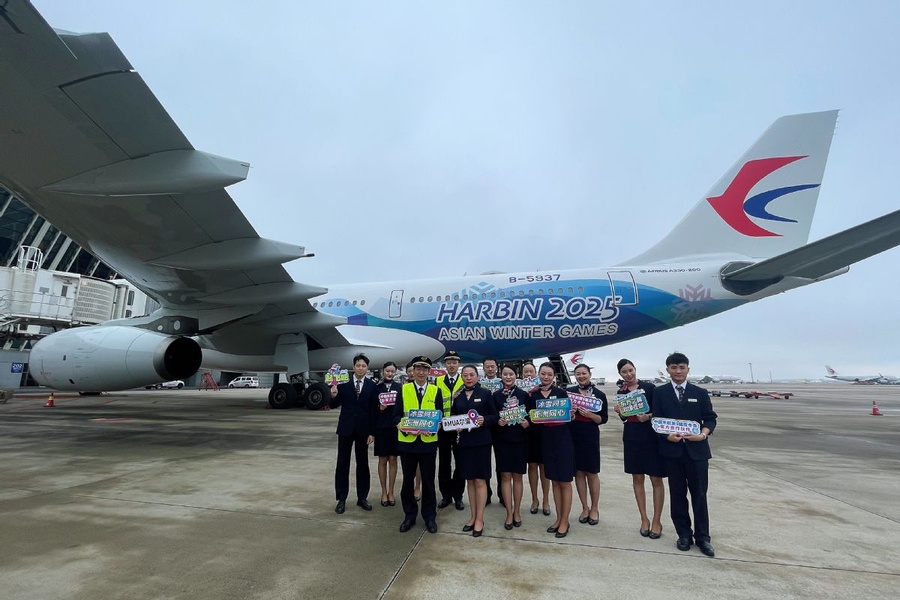 Aircrew members of the China Eastern Airlines pose for a group photo in front of the themed aircraft for the upcoming 2025 Harbin Asian Winter Games unveiled by the carrier on November 16. [Photo provided to chinadaily.com.cn]